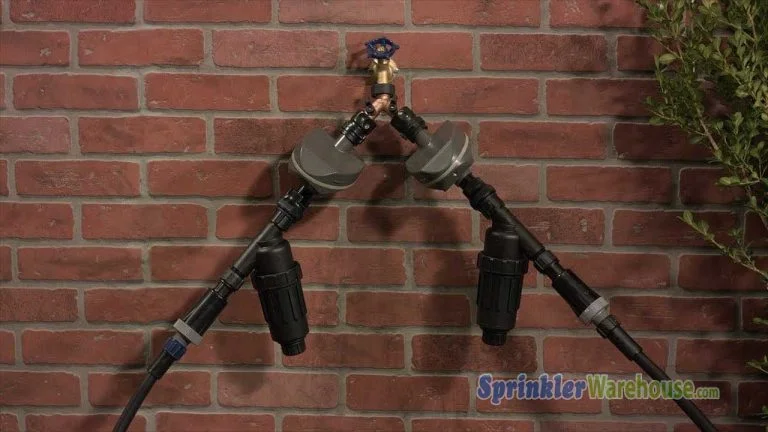 Tutorials Install & Design 17 This video thumbnail shows a hose spigot with 2 drip system bib connections attached with a Y ball valve on a brick background.