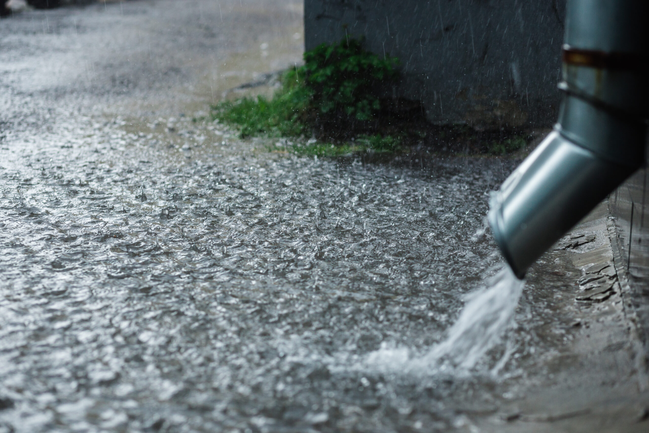 Rain water flowing from a metal downspout during a heavy rain. concept of protection against heavy rains.