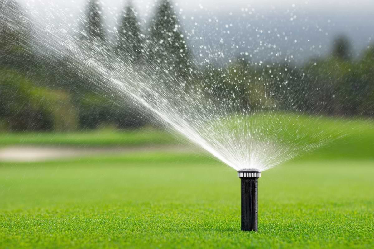 Golf Course Irrigation: Make Your System a Hole-in-One 1 Sprinkler rotor watering grass on a golf course during the day.