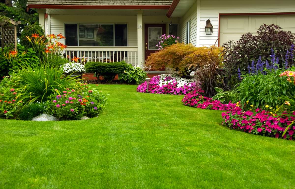 Gardening Zones Guide: How to Use a Growing Zones Map & More Tips for Plant Health 1 Beautiful, diverse gardens in a front yard leading up to the porch of a modest home and en suite garage.