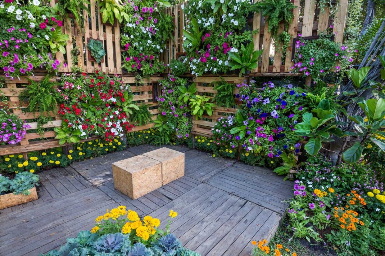 Outdoor courtyard enclosed by a vibrant vertical wall garden of colorful flowers and green plants.