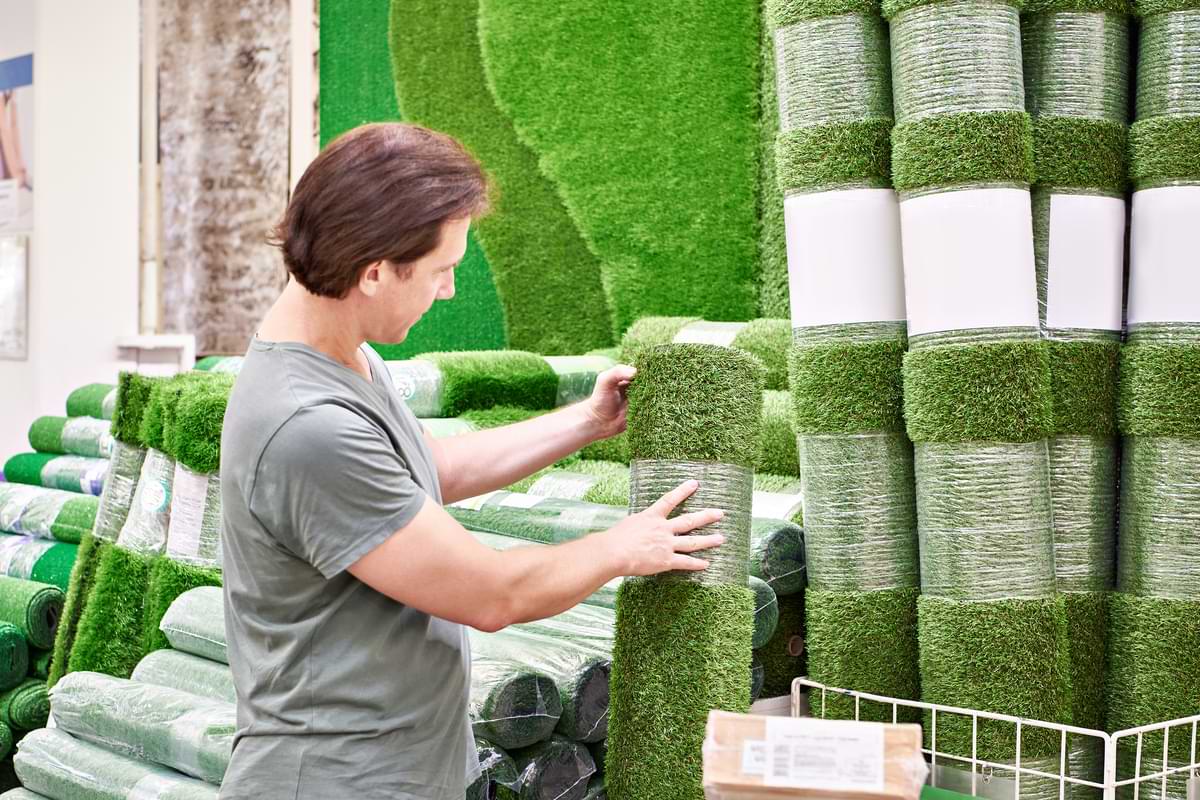 Is Turf Real Grass? 1 Man inspecting a vertical row of turf grass in a store.