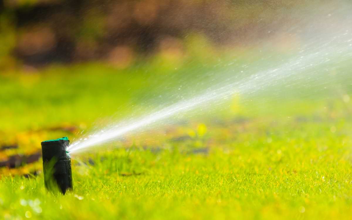 How to Design Commercial Sprinkler Systems in 6 Steps 1 Rain Bird sprinkler rotor spraying a stream of water across green grass.