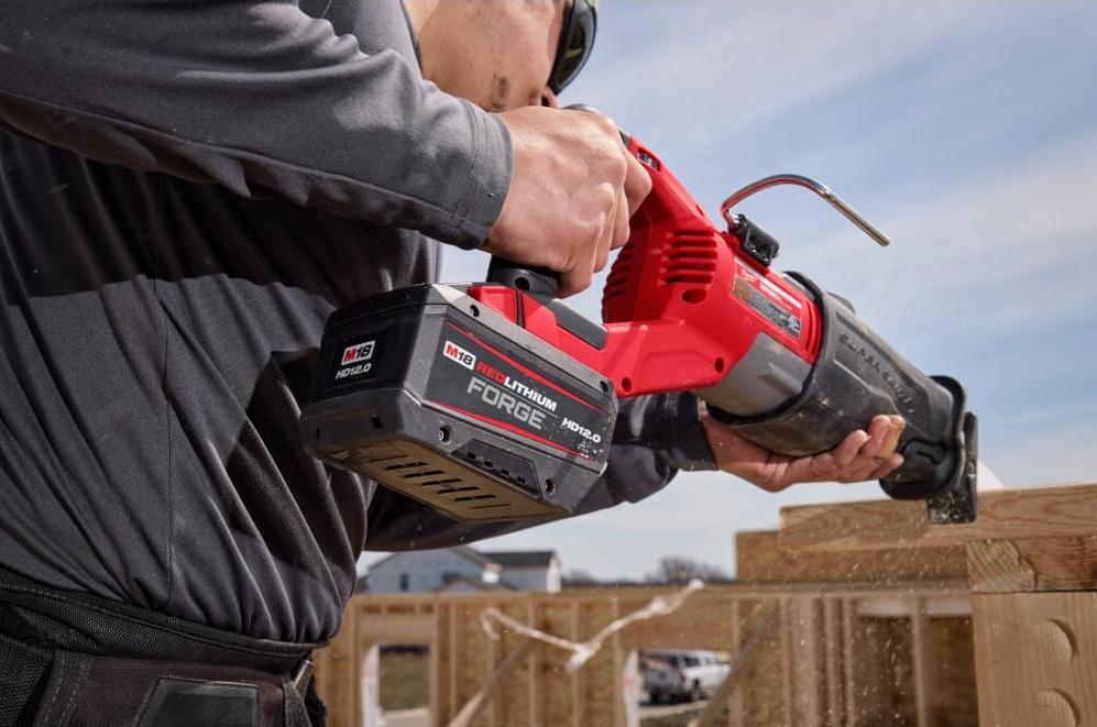 Maintenance 2 Man cutting a strip of wood with a Milwaukee Tool reciprocating saw during a construction project.