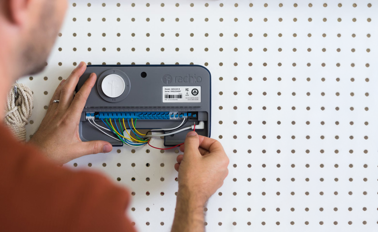 WiFi Irrigation Controller Guide: How to Set up a WiFi Controlled Sprinkler 1 Man fixing a wire from the back of a Rachio sprinkler controller.