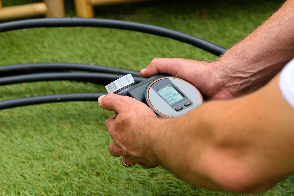 Drip Irrigation for Vegetable Gardens 4 Man programming a hose timer in his backyard.