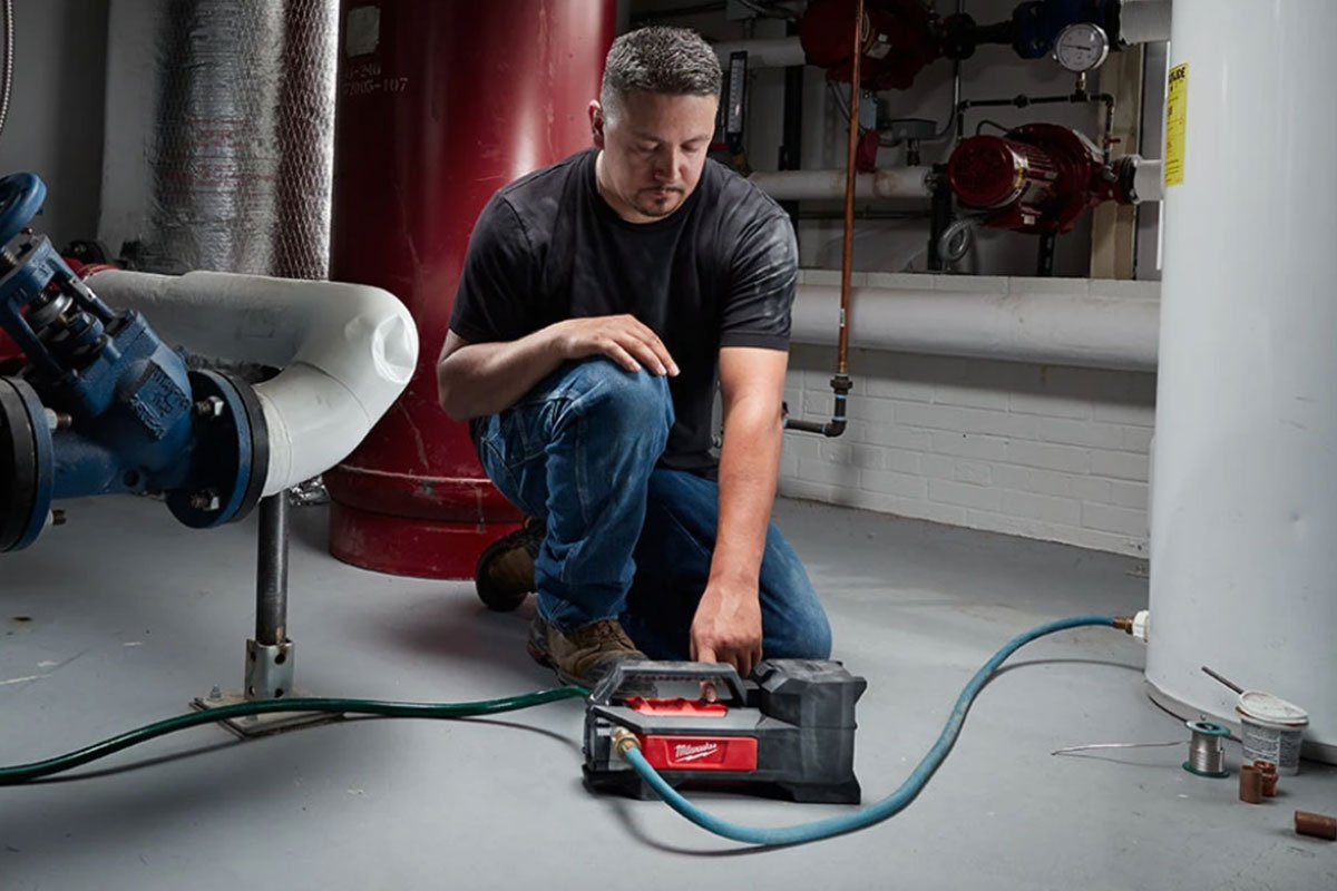 Milwaukee FUEL™: Milwaukee M18 & Milwaukee M12 for Professional Landscapers & DIYers 1 Man with Milwaukee transfer pump connected to hoses.