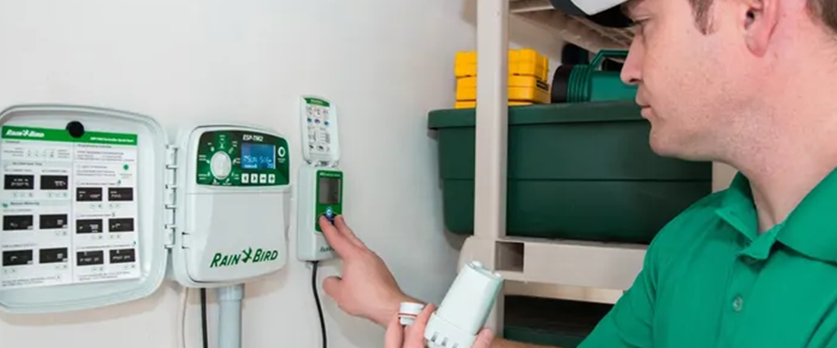 Slope Irrigation Guide: DIY Tips for Gardening on a Sloped Lawn 2 Technician connecting a sprinkler controller and moisture sensor against a white garage wall.