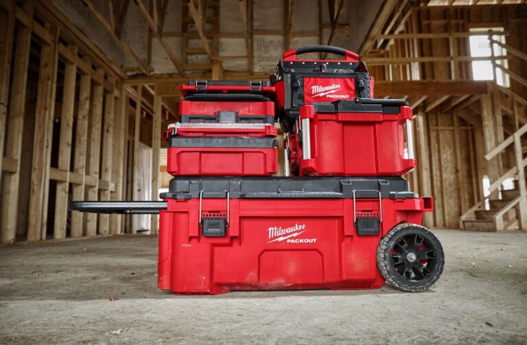 Milwaukee PACKOUT tool box collection in a construction jobsite with wood framing in the background.