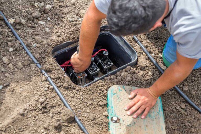 Man adjusting a sprinkler valve underground.