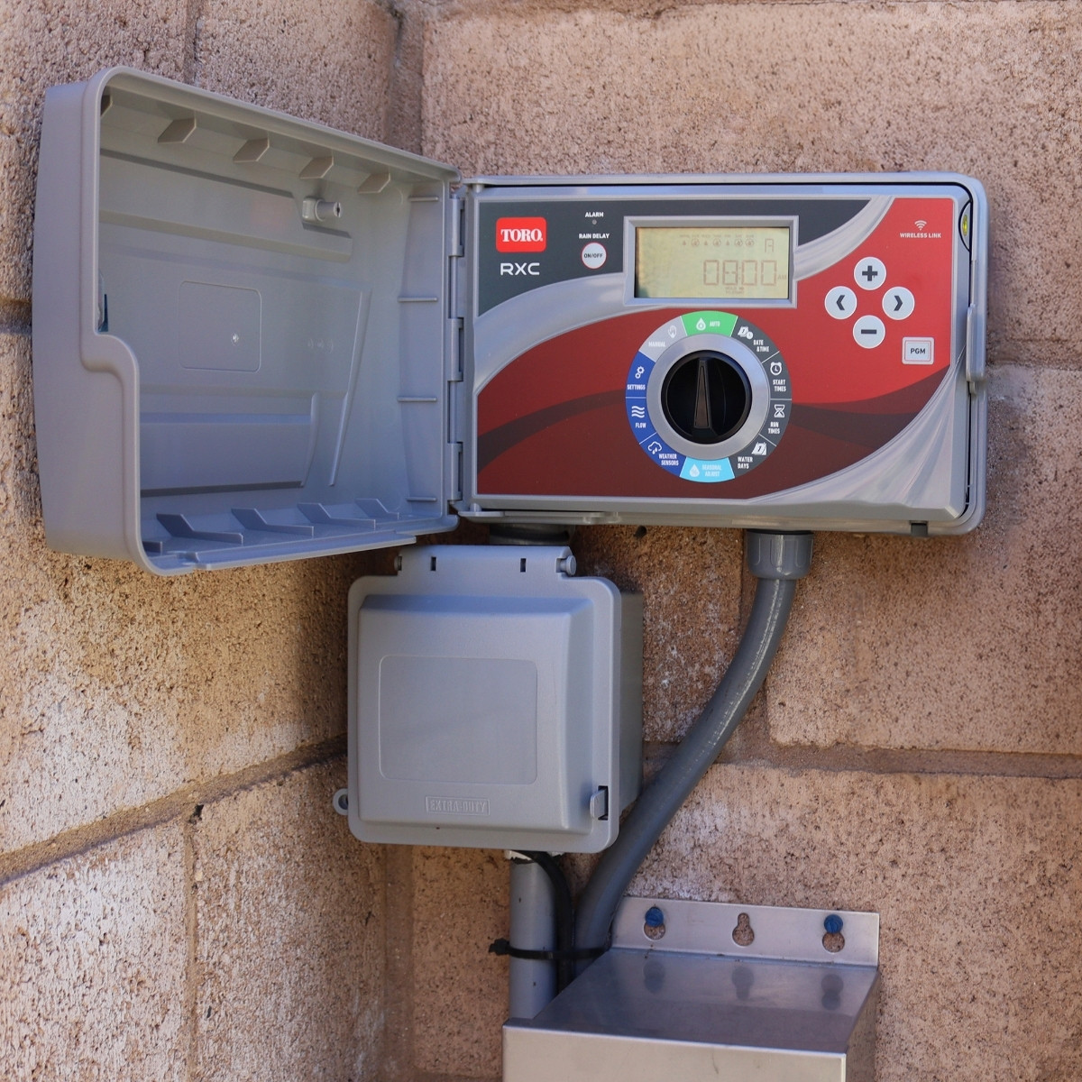 Toro RXC controller open and mounted on exterior brick wall.