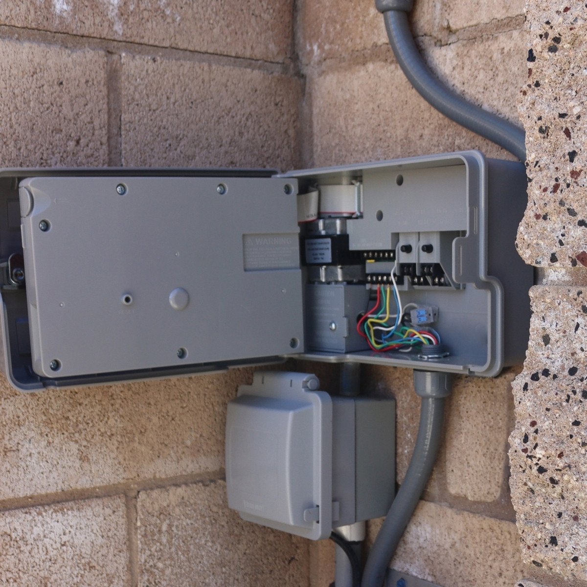 Open Toro RXC controller mounted on a brick exterior wall.